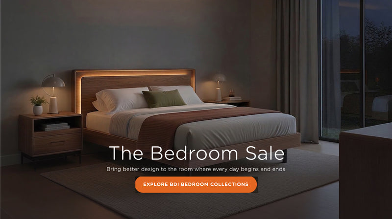 The Bedroom Sale banner promoting BDI bedroom collections, featuring a modern bedroom scene with a low wooden bed frame, integrated warm LED backlighting, matching wood nightstands, and a dark gray textured rug.